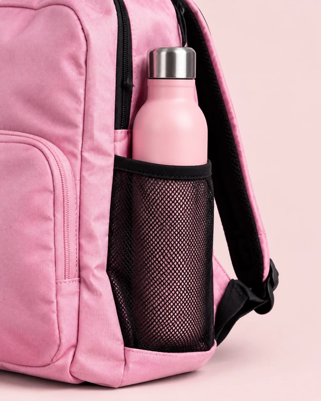 Pink water bottle in the mesh side pocket of a dance backpack
